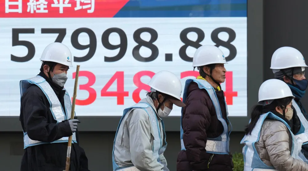 مشاة يمرون أمام شاشة تعرض حركة الأسهم في وسط العاصمة اليابانية طوكيو (أ.ب)