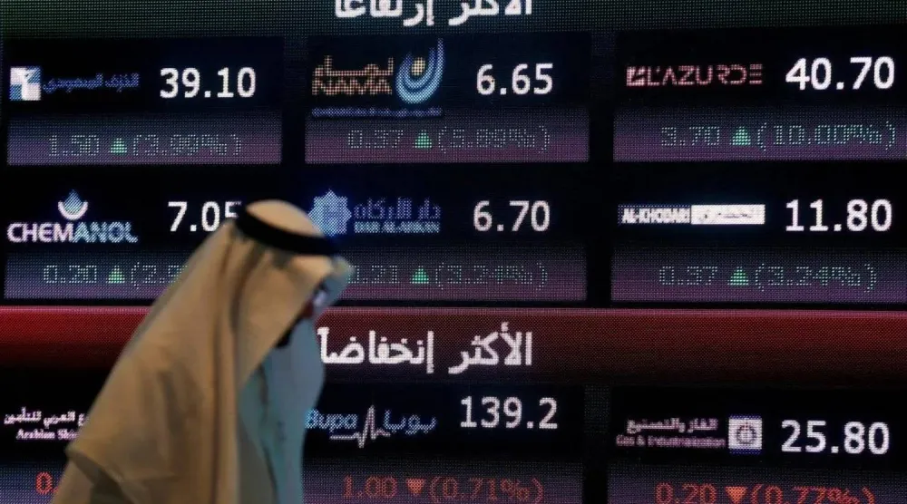 مستثمر يمر أمام شاشة تعرض معلومات «سوق الأسهم السعودية» في الرياض (رويترز)