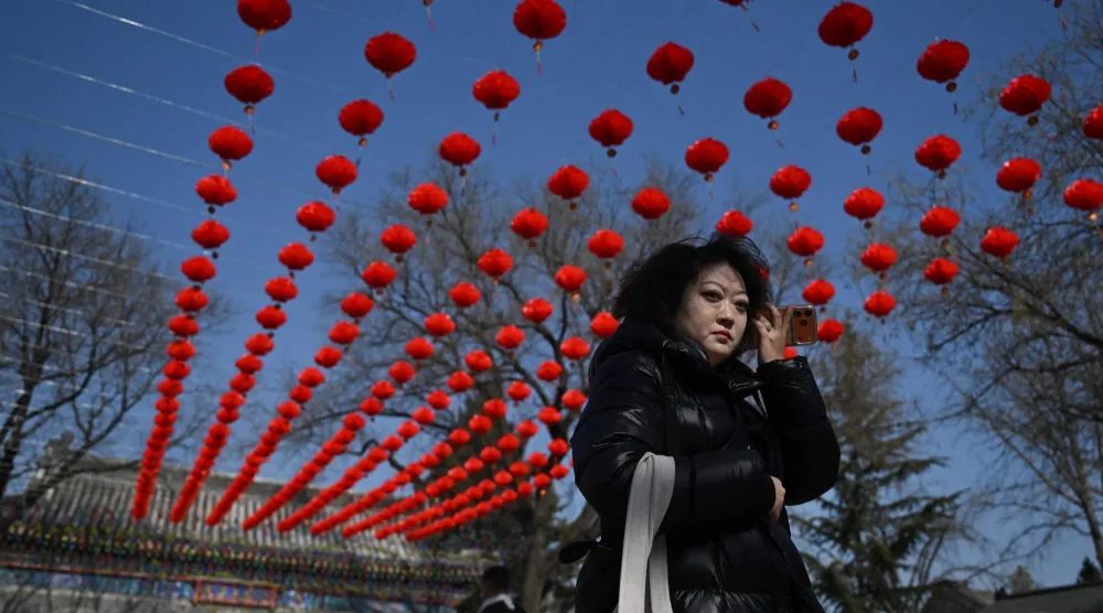 امرأة تسير تحت زينة العام الجديد بأحد المعابد في العاصمة الصينية بكين (أ.ف.ب)