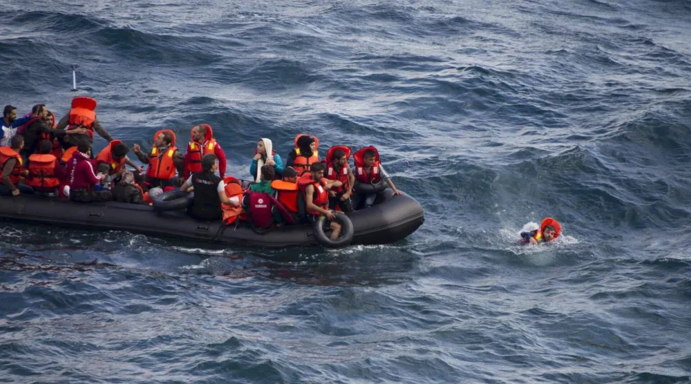 مهاجر يسبح بجوار قارب مطاطي مكتظ بالمهاجرين قرب شواطئ جزيرة ليسبوس اليونانية أثناء عبوره جزءاً من بحر إيجه من الساحل التركي (رويترز - أرشيفية)