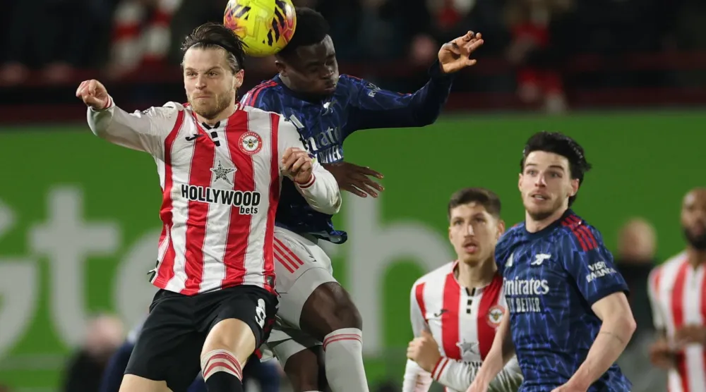 إيثان بينوك لاعب برينتفورد وبوكايو ساكا لاعب أرسنال يرتقيان لالتحام هوائي على الكرة (أ.ب)