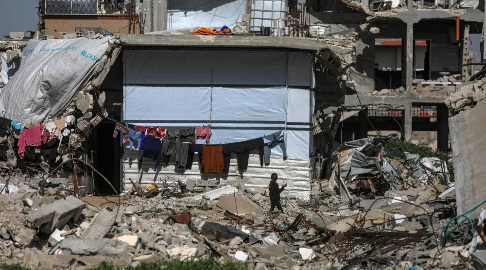 فتاة نازحة تسير أمام خيمة عائلتها وسط أنقاض بحي الزيتون في مدينة غزة أمس (إ.ب.أ)