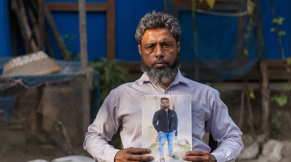 البنغلاديشي محمد سيراج يحمل صورة ابنه سجاد (20 عاماً) الذي قتل على الجبهة الروسية (أ.ب)