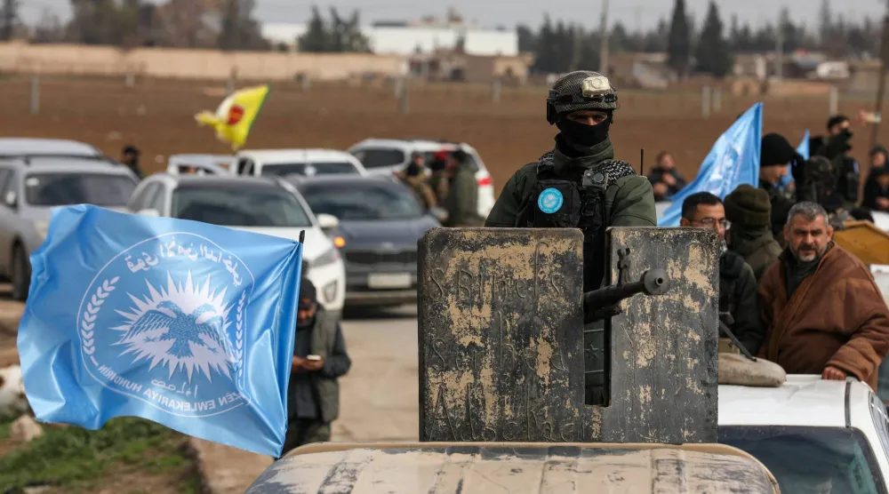 يقوم أحد أفراد قوات الأمن الداخلي الكردية بتشغيل مدفع رشاش مثبت على مركبة في حين يتجه هو وآخرون نحو خطوط المواجهة على مشارف مدينة تل حمس عقب الاتفاق بين «قسد» وحكومة دمشق (رويترز)