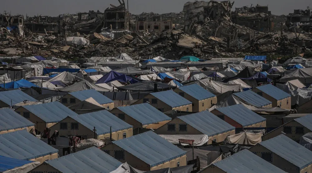 خيام تؤوي مئات النازحين وفي الخلفية الدمار الهائل بعد عامين من القصف الإسرائيلي في حي الزيتون شرق مدينة غزة (إ.ب.أ)