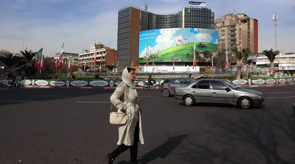 An Iranian woman walks past an anti-US billboard at Valiasr Square in Tehran, Iran, 14 February 2026, amid heightened regional tensions following an increased US military presence in the Middle East. (EPA)
