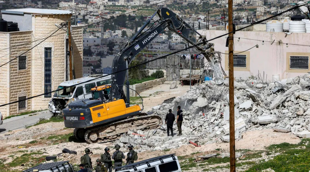 حفار تستخدمه قوات الأمن الإسرائيلية يهدم مبنى في قرية بيت غوا في الضفة الغربية المحتلة (أ.ف.ب)