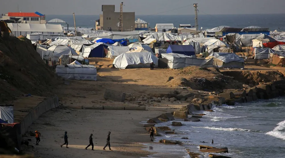 يسير الناس بالقرب من الخيام التي تؤوي الفلسطينيين النازحين في منطقة مواصي خان يونس جنوب قطاع غزة (أ.ف.ب)