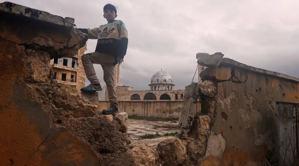 طفل يقف على جدار مدرسة متضررة في حي الشيخ مقصود ذي الأغلبية الكردية في حلب بسوريا السبت 14 فبراير 2026