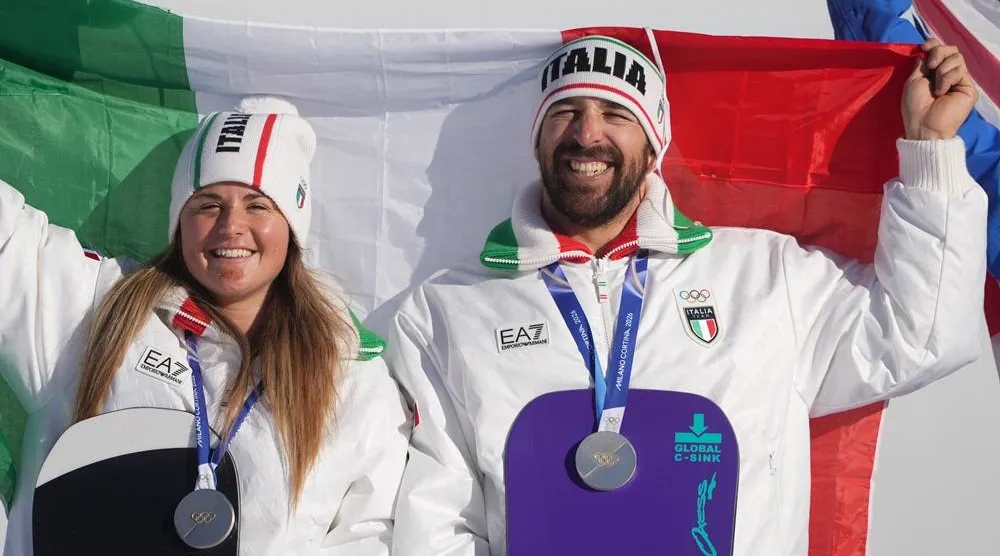  Silver medalists Italy's Michela Moioli and Lorenzo Sommariva hold an Italian flag as they celebrate after the mixed team snowboard cross finals at the 2026 Winter Olympics, in Livigno, Italy, Sunday, Feb. 15, 2026. (AP) 