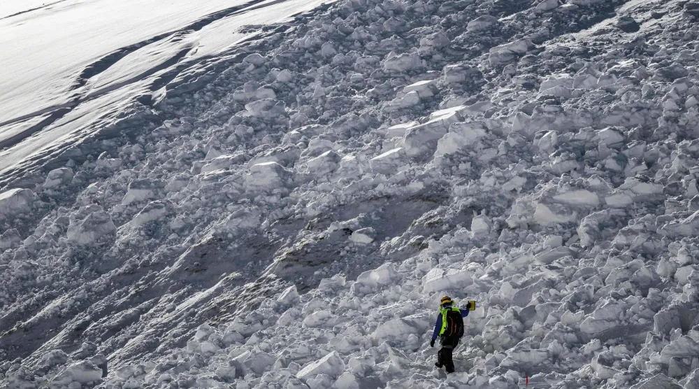 A member of the CRS Alpes Grenoble mountain rescue team operates as he searches for potential buried victims during an avalanche emergency response rescue mission in an off-piste area of the Ecrins massif, French Alps on January 29, 2026. (Photo by JEFF PACHOUD / AFP)