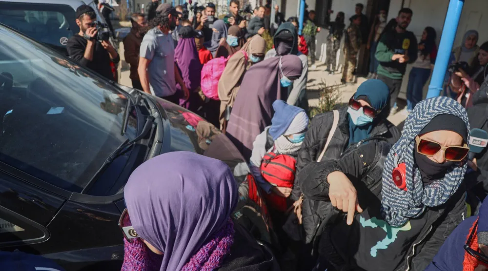 Family members of suspected ISIS militants who are Australian nationals walk toward a van bound for the airport in Damascus during the first repatriation operation of the year at Roj Camp in eastern Syria, Monday, Feb. 16, 2026. (AP Photo/Baderkhan Ahmad)