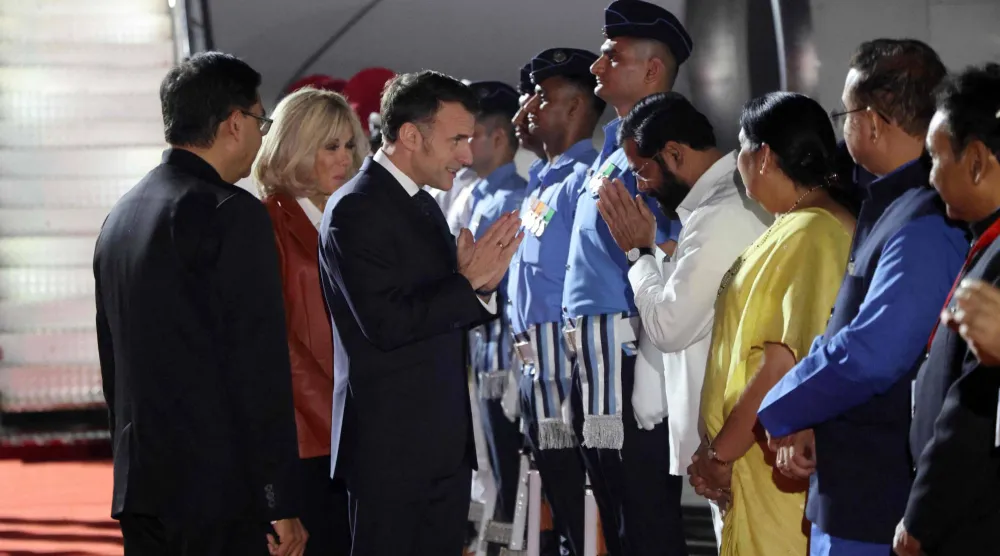 France's President Emmanuel Macron (C-R) and his wife Brigitte Macron (C) are welcomed by India's officials upon their arrival in Mumbai on February 17, 2026. (Photo by Ludovic MARIN / AFP)
