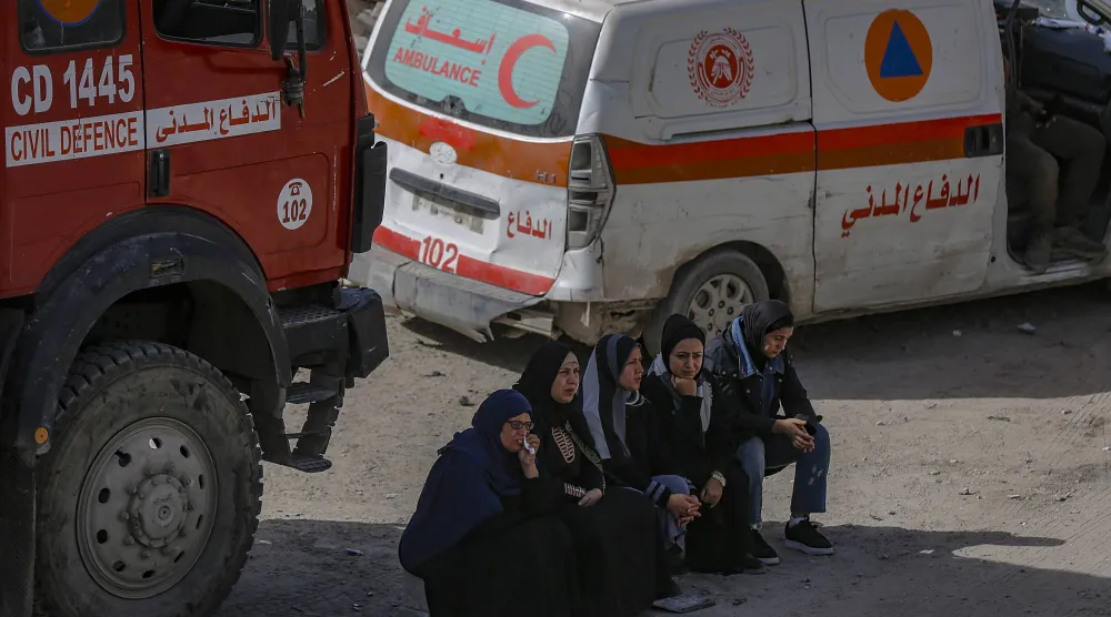 A group of women wait for news as Palestinian civil defense teams work to recover the remains of 67 members of the Abu Nasr family from beneath the rubble of their home after it was destroyed in an Israeli airstrike in Beit Lahiya, north of Gaza City, 15 February 2026. (EPA)