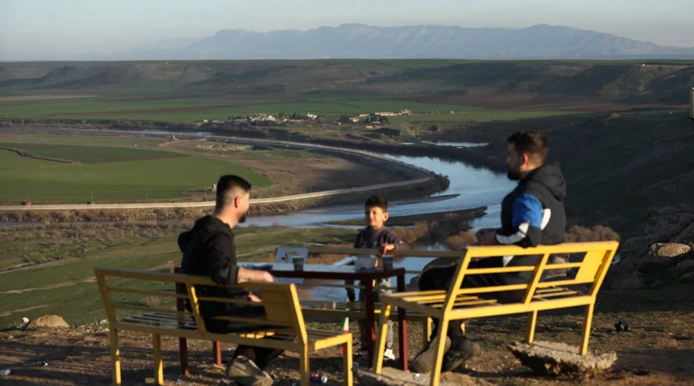 سكان من ديريك قرب الحدود السورية التركية بعد منخفض جوي ويبدو نهر دجلة (رويترز)