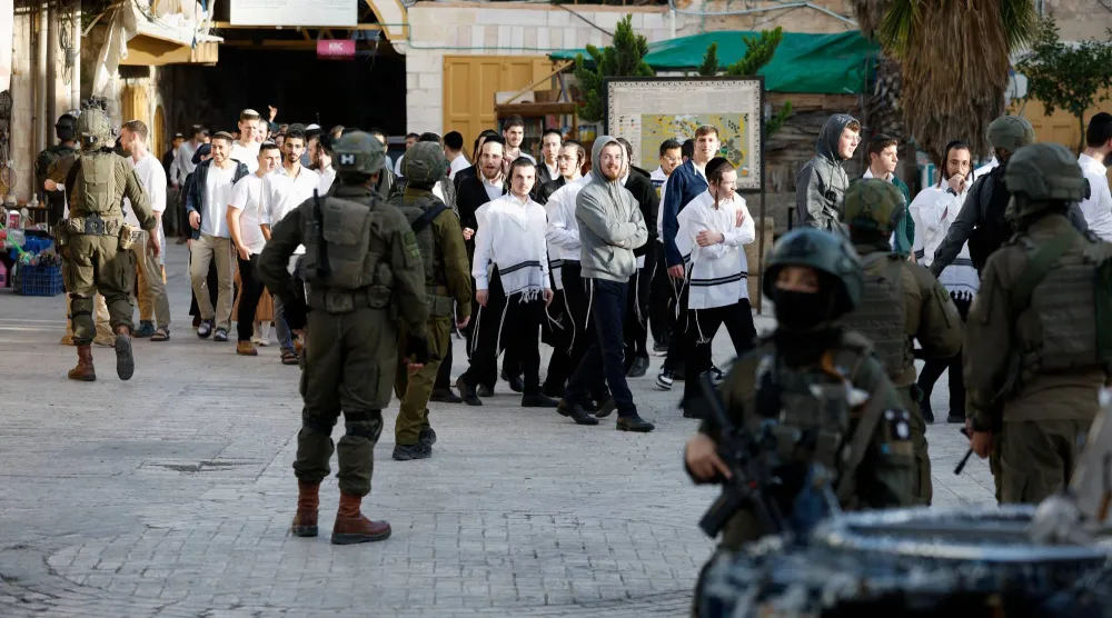 جنود إسرائيليون يقفون للحراسة خلال جولة للمستوطنين في الخليل بالضفة الغربية المحتلة (رويترز)