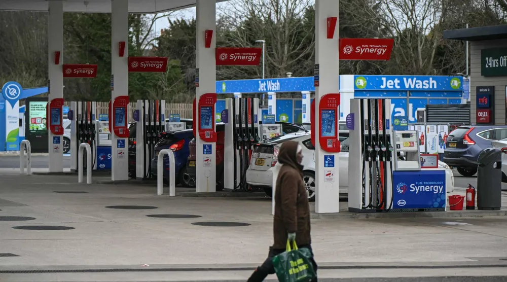 إمرأة تمر أمام صف من مضخات الوقود في محطة بنزين بمنطقة واندزورث جنوب غرب لندن (أ.ف.ب)