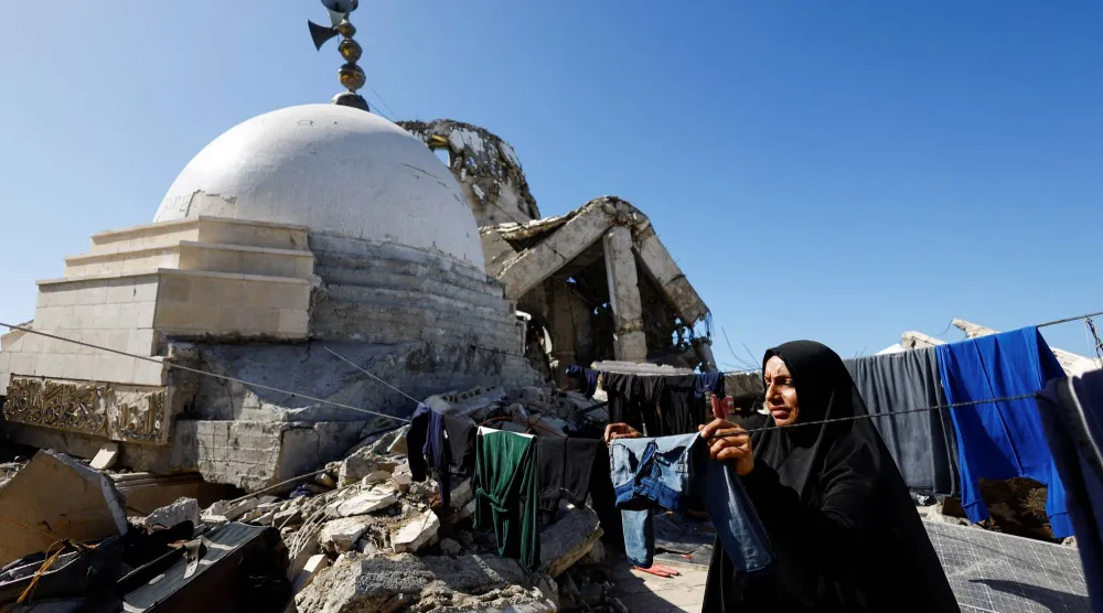 امرأة فلسطينية نازحة تعيش قرب مسجد دُمر خلال القصف الإسرائيلي على مدينة غزة (رويترز)