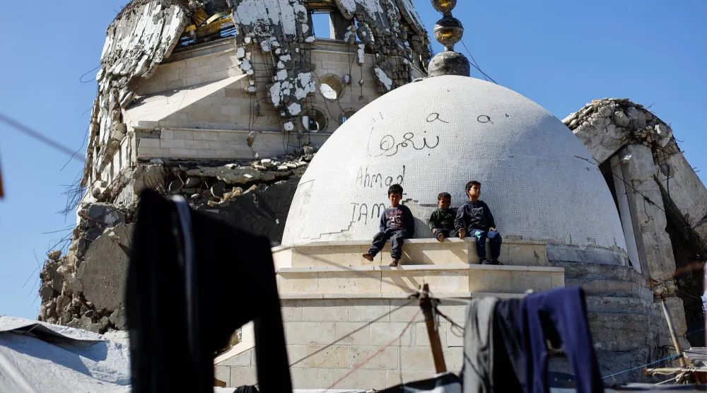 أطفال يجلسون أمام مسجد دُمّر بفعل العدوان الإسرائيلي في مدينة غزة أمس (رويترز)