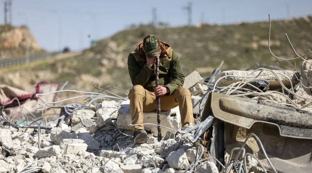 فلسطيني يبكي وهو يجلس على أنقاض مبنى سكني بعد أن هدمته جرافات إسرائيلية قرب مستوطنة حغاي الإسرائيلية جنوب مدينة الخليل بالضفة الغربية المحتلة (أ.ف.ب)