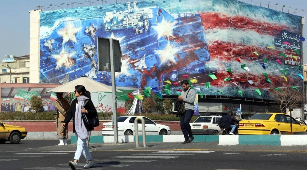 يعبر أحد المشاة الشارع بالقرب من لوحة إعلانية مناهضة للولايات المتحدة في طهران (إ.ب.أ)