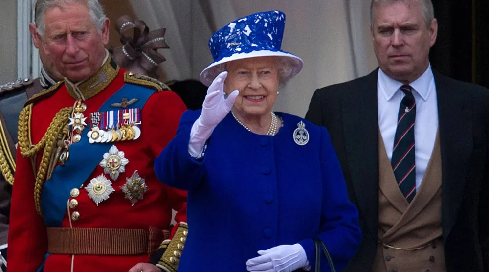 الملكة البريطانية إليزابيث الثانية تلوّح بيدها من شرفة قصر باكنغهام محاطة بابنيها الأمير تشارلز أمير ويلز (على اليسار) والأمير أندرو دوق يورك (على اليمين) عقب عرض عيد ميلاد الملكة في وسط لندن يوم 15 يونيو 2013 (أ.ف.ب)