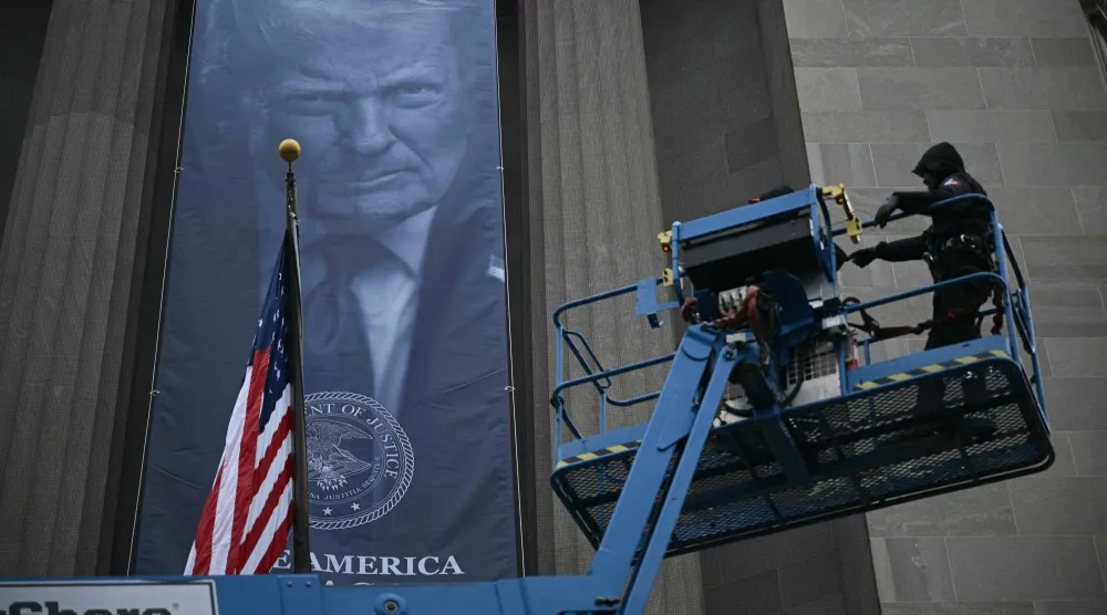 عمال يقومون بتركيب لافتة جديدة تحمل صورة الرئيس الأميركي دونالد ترمب على واجهة مبنى مقر وزارة العدل الأميركية في واشنطن (أ.ف.ب)