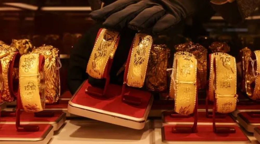 موظف يعرض زوجاً من الأساور الذهبية المخصّصة لحفلات الزفاف الصينية داخل محل للمجوهرات في هونغ كونغ (رويترز)