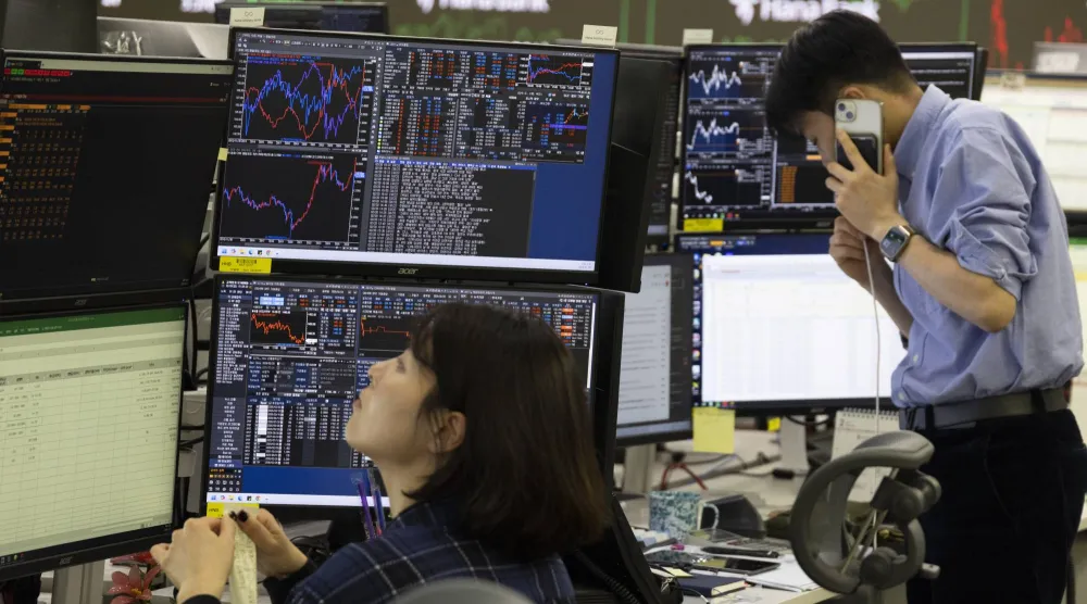متعاملون كوريون جنوبيون يعملون أمام شاشات تعرض مؤشرات الأسهم في بنك هانا في سيول (إ.ب.أ)
