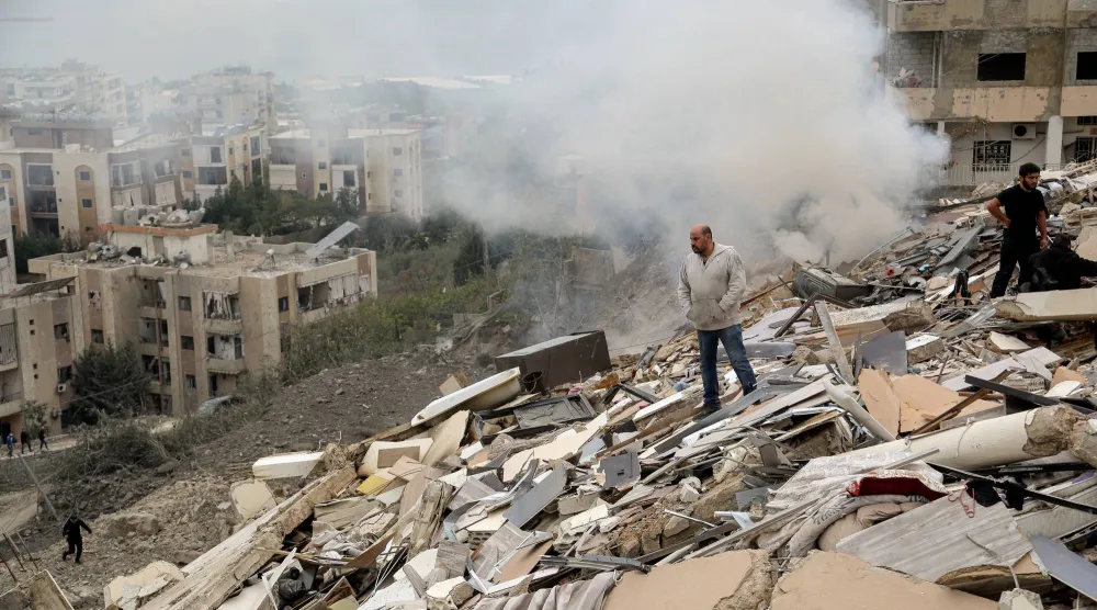 22 January 2026, Lebanon, Qnarit: People inspect the damage of a building that was destroyed by an Israeli air raid on the southern Lebanese village of Qnarit. (dpa)