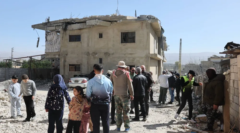 عدد من المواطنين يتفقدون الأضرار الناجمة عن قصف مبنى في بلدة تمنين في البقاع مساء الجمعة (إ.ب.أ)