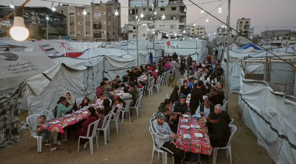 فلسطينيون يتجمعون لتناول الإفطار خارج خيامهم في معسكر للنازحين بمدينة غزة الجمعة (أ.ب)