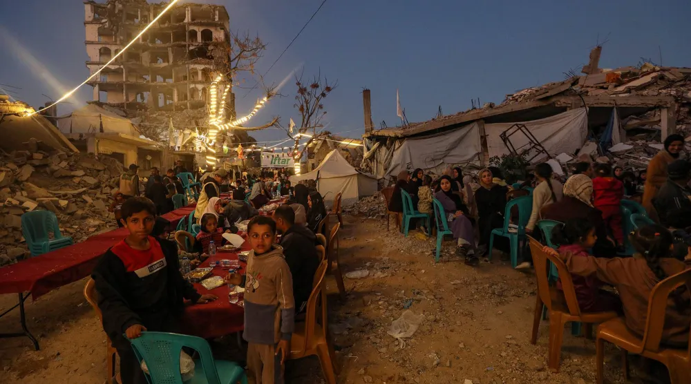 فلسطينيون يتجمعون لوجبة الإفطار بين أنقاض المنازل شمال قطاع غزة (إ.ب.أ)