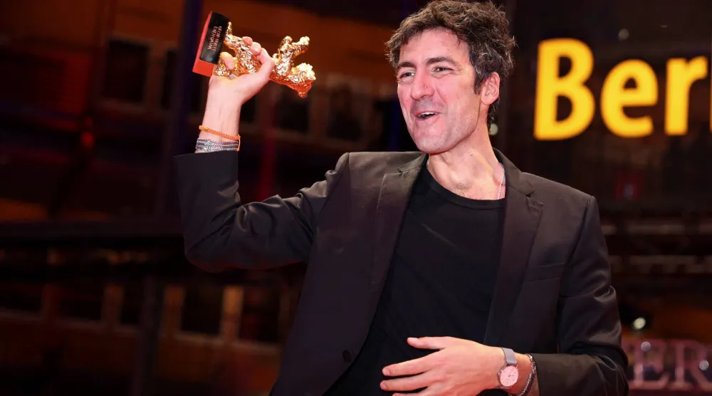 المخرج الألماني إيلكر كاتاك يرفع جائزة الدب الذهبي لأفضل فيلم في مهرجان برلين السينمائي (رويترز) 