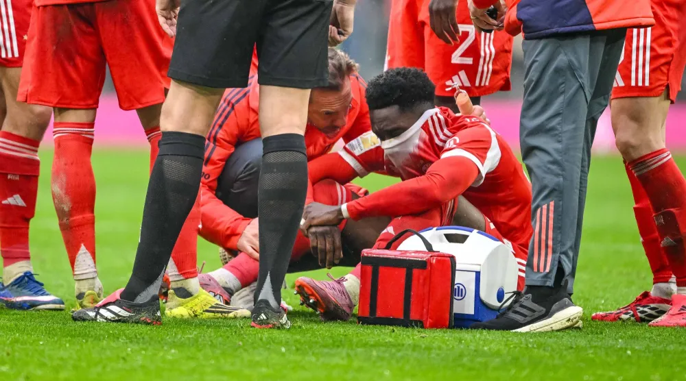 21 February 2026, Bavaria, Munich: Bayern Munich's Alphonso Davies (R) sits injured on the ground during the German Bundesliga soccer match between Bayern Munich and Eintracht Frankfurt at Allianz Arena. Photo: Harry Langer/dpa 