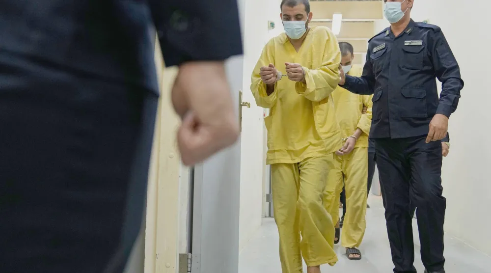 رجل أمن عراقي مع عناصر من «داعش» في «سجن الكرخ» ببغداد (أ.ب)