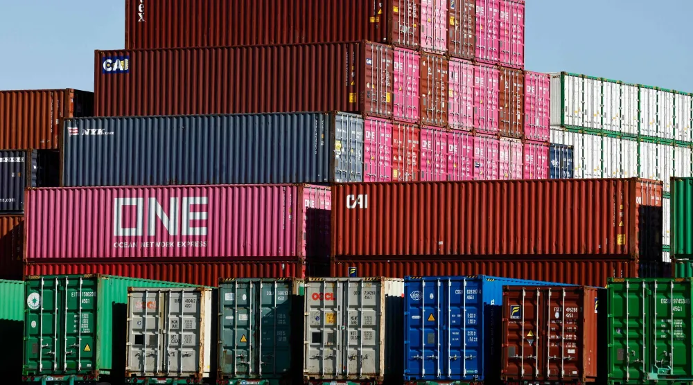 حاويات شحن مكدسة بينما تستقر أخرى على هياكل شاحنات نقل بميناء لوس أنجليس (أ.ف.ب)