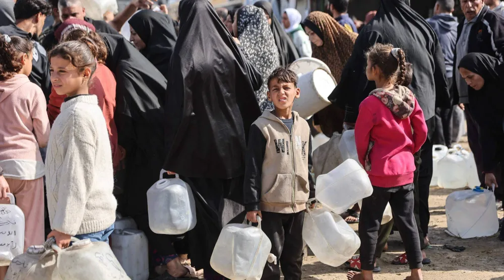 نازحون فلسطينيون ينتظرون ملء المياه في مخيم الرمال بمدينة غزة أول من أمس (أ.ف.ب)