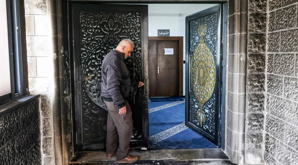 آثار حريق على باب مسجد أبو بكر الصديق في قرية تل غرب نابلس بعدما سكب مستوطنون مواد قابلة للاشتعال عند مدخل المسجد (أ.ف.ب)
