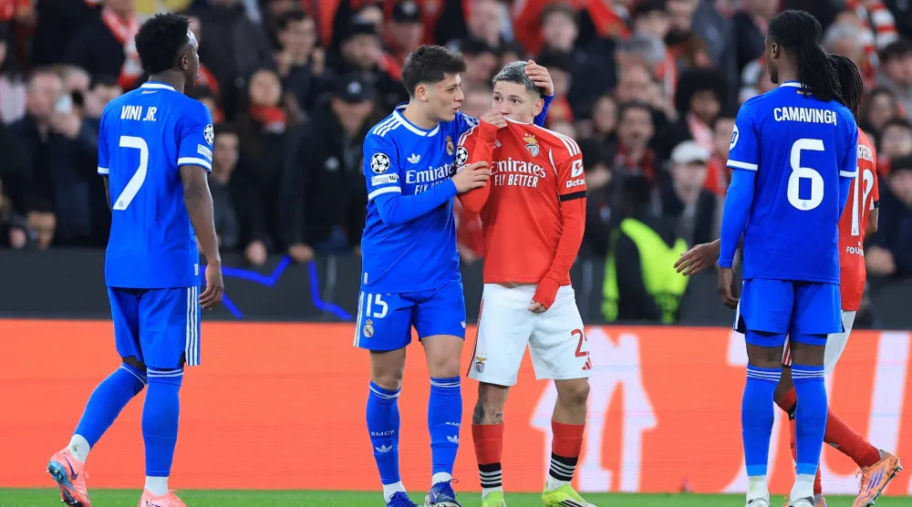 SL Benfica's Argentine forward #25 Gianluca Prestianni hides his mouth while arguing with Real Madrid's Brazilian forward #07 Vinícius Júniorwho complained about alleged racists insults during the UEFA Champions League knockout round play-off first leg football match between SL Benfica and Real Madrid CF at Estadio da Luz in Lisbon on February 17, 2026. (AFP) 