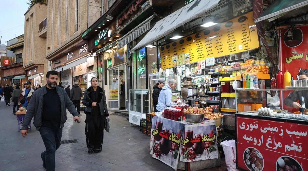 Iranians walk past shops selling food ahead of Iftar, the Ramadan fast-breaking meal, in northern Tehran on February 23, 2026. (AFP)