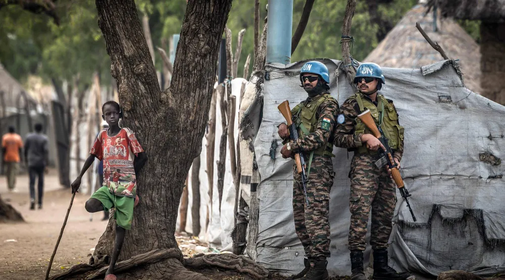 جنود حفظ سلام هنود يعملون مع بعثة الأمم المتحدة في جنوب السودان يقفون حراساً بجانب صبي صغير أثناء قيامهم بدورية خارج مكاتب الحكومة المحلية ببلدة أكوبو الاستراتيجية التي تسيطر عليها المعارضة في ولاية جونقلي 12 فبراير 2026 (أ.ف.ب)