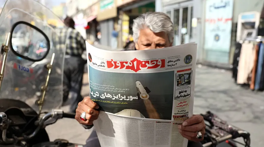 İranlı bir adam, Devrim Muhafızları Ordusu’na (DMO) yakın bir gazete olan Vatan Emruz’un bir nüshasını elinde tutuyor. Gazetenin ön sayfasında ‘Tahran’da deniz sürprizleri’ başlığı altında bir füze resmi yer alıyor. (EPA)
