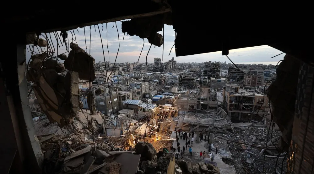 نازحون يتجمعون لتناول وجبة إفطار رمضان وسط أنقاض المباني المدمرة في مخيم جباليا للاجئين شمال قطاع غزة (أ.ف.ب)