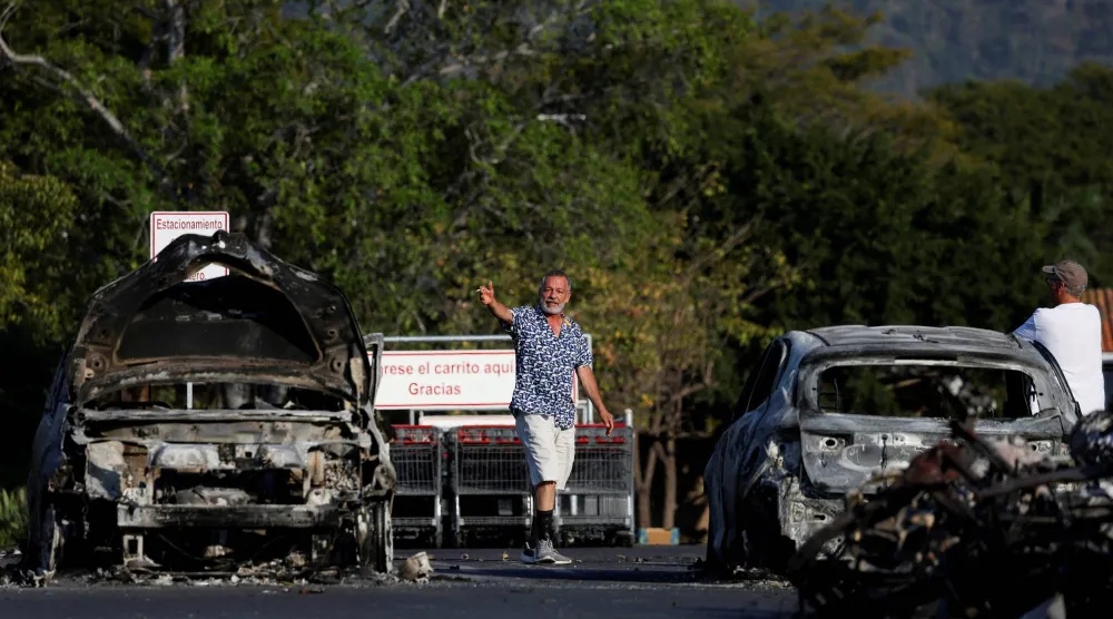 People walk at a parking lot of a supermarket where several vehicles were consumed by flames days after a series of blockades and attacks by organized crime following a military operation in which drug cartel leader Nemesio Oseguera, known as "El Mencho," was killed, in Puerto Vallarta, Mexico, February 24, 2026. REUTERS/Daniel Becerril