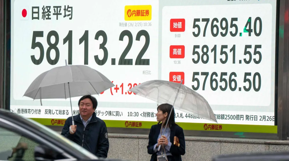 مارة يسيرون أمام شاشة تعرض حركة الأسهم في وسط العاصمة اليابانية طوكيو (أ.ف.ب)