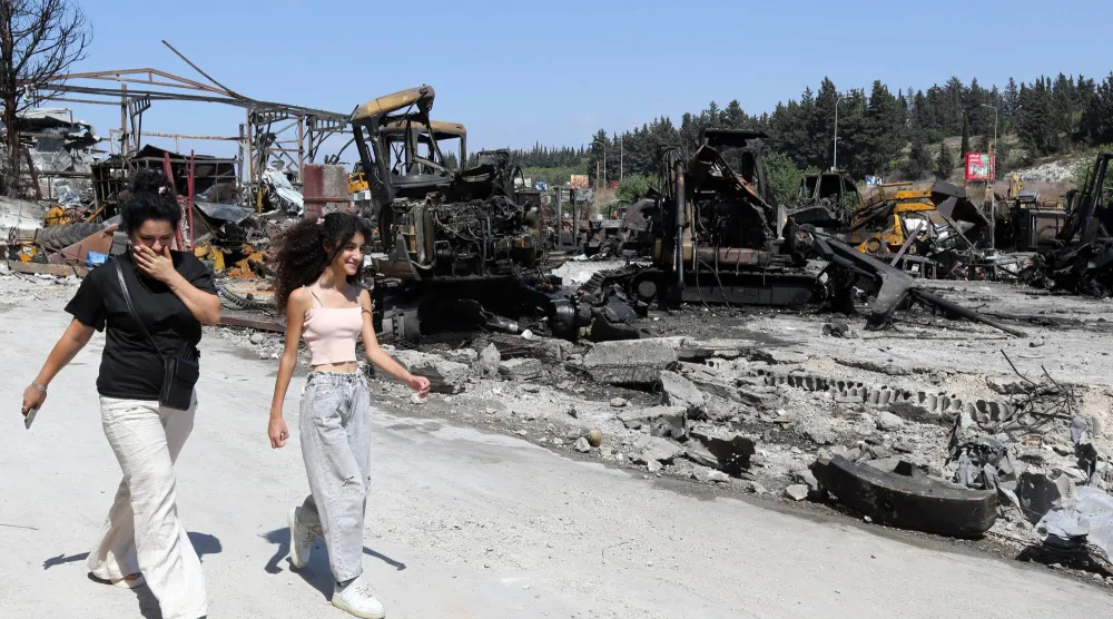 لبنانيتان تسيران قرب موقع استهدفته إسرائيل كان لباحة صيانة جرافات ببلدة أنصار جنوب لبنان خلال سبتمبر 2025 (أرشيفية - إ.ب.أ)