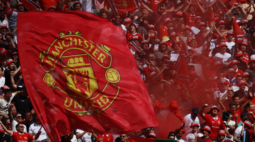 جماهير مانشستر يونايتد ترفع شعار النادي (رويترز)