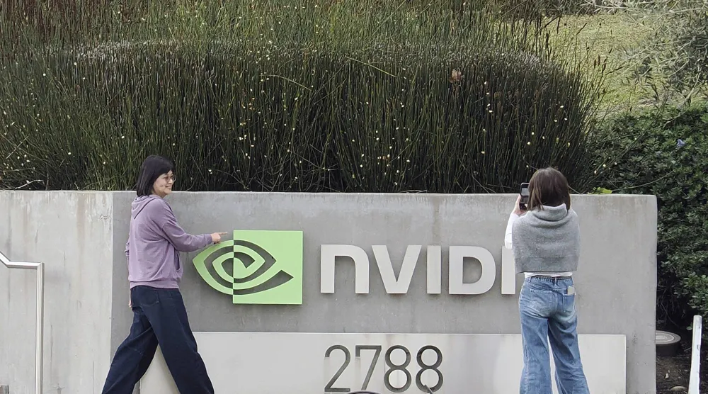 شخصان يلتقطان صوراً لشعار شركة «إنفيديا» خارج مقرها الرئيسي في سانتا كلارا بكاليفورنيا (إ.ب.أ)