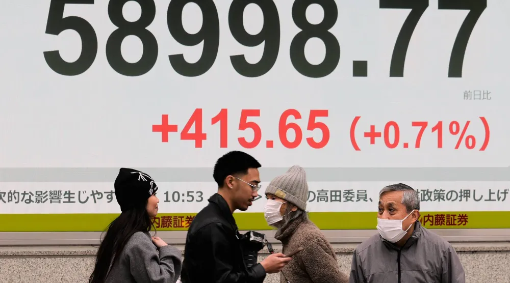 مشاة يمرون أمام شاشة إلكترونية تعرض حركة الأسهم وسط العاصمة اليابانية طوكيو (أ.ب)